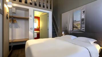 A hotel room with a bed, a wardrobe, a bathroom, and a staircase.