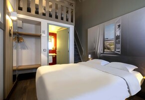 Una habitación de hotel con cama, armario, baño y escalera.