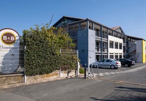 A B&B hotel with a signboard, a parking area, and a building with multiple floors and balconies.