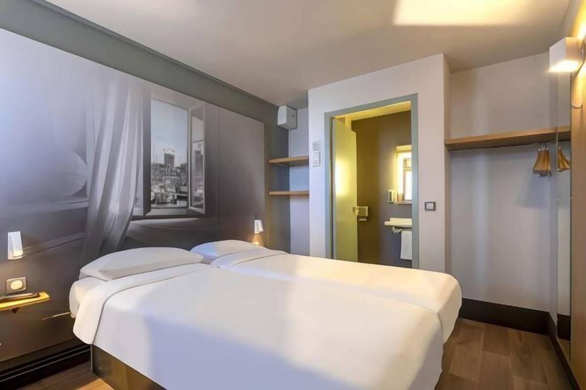 A hotel room with a bed, a nightstand, a wardrobe, and a mirror.