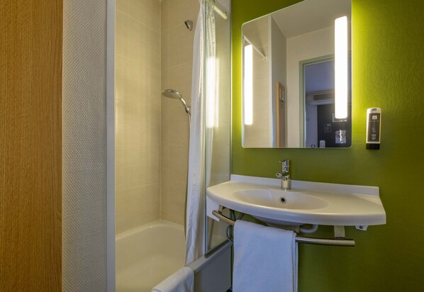 A bathroom with a bathtub, a white sink, and a mirror. - B&B Hotel La Rochelle Angoulins sur mer (Angoulins)