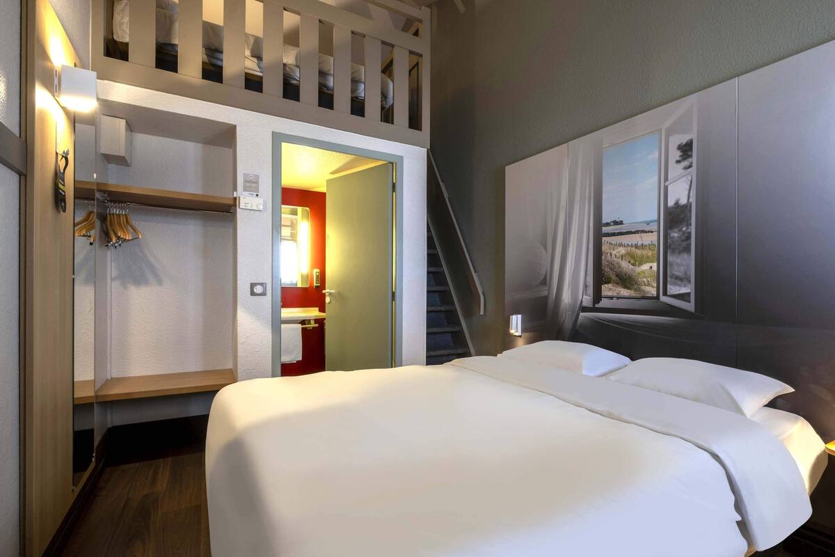 A hotel room with a bed, a wardrobe, a bathroom, and a staircase.