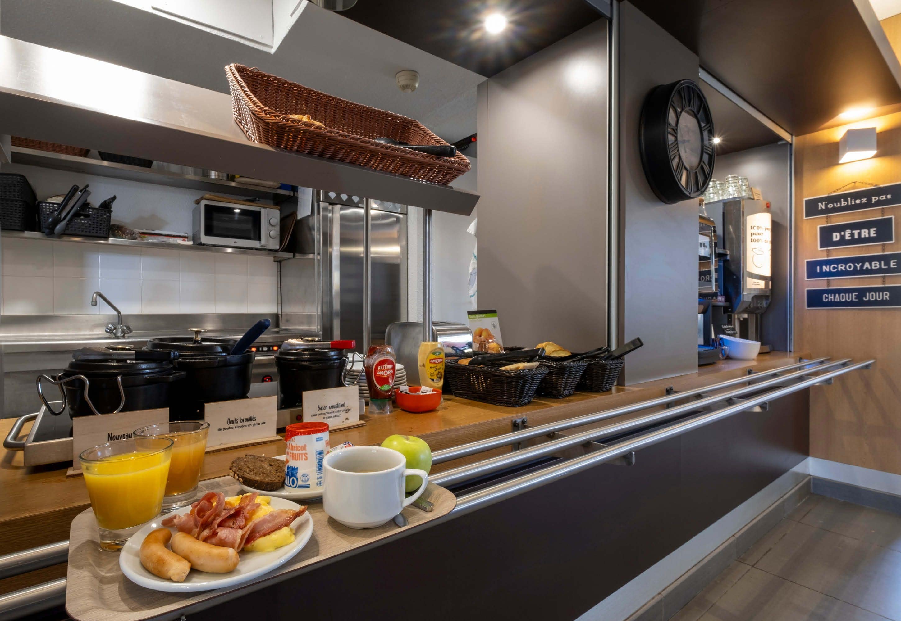 A breakfast bar with a variety of food items, including toast, eggs, bacon, and fruit. There are also two glasses of orange juice and a coffee cup.