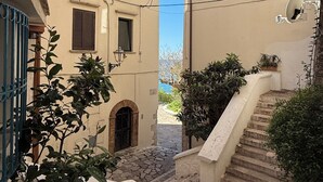 A narrow street with buildings, a stone staircase, and greenery. - Casa Vacanza Eos (Sperlonga)