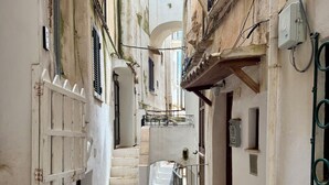 A narrow alleyway with a staircase leading to a higher level, surrounded by old buildings with balconies and a white wall. - Casa Vacanza Eos (Sperlonga)