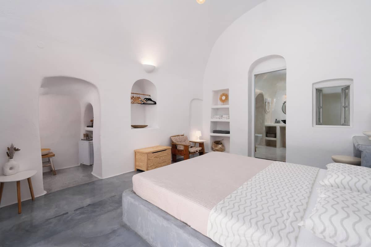 Een minimalistische slaapkamer met een groot bed, een klein bureau en een inloopkast.