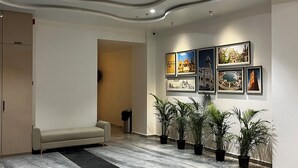 A spacious lobby with a marble floor, a sofa, potted plants, and framed pictures on the wall. - Hotel the octave (Surat)
