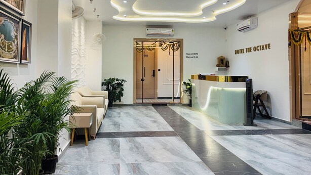A hotel lobby with a modern design, featuring a reception desk, seating area, and a decorative ceiling. - Hotel the octave (Surat)