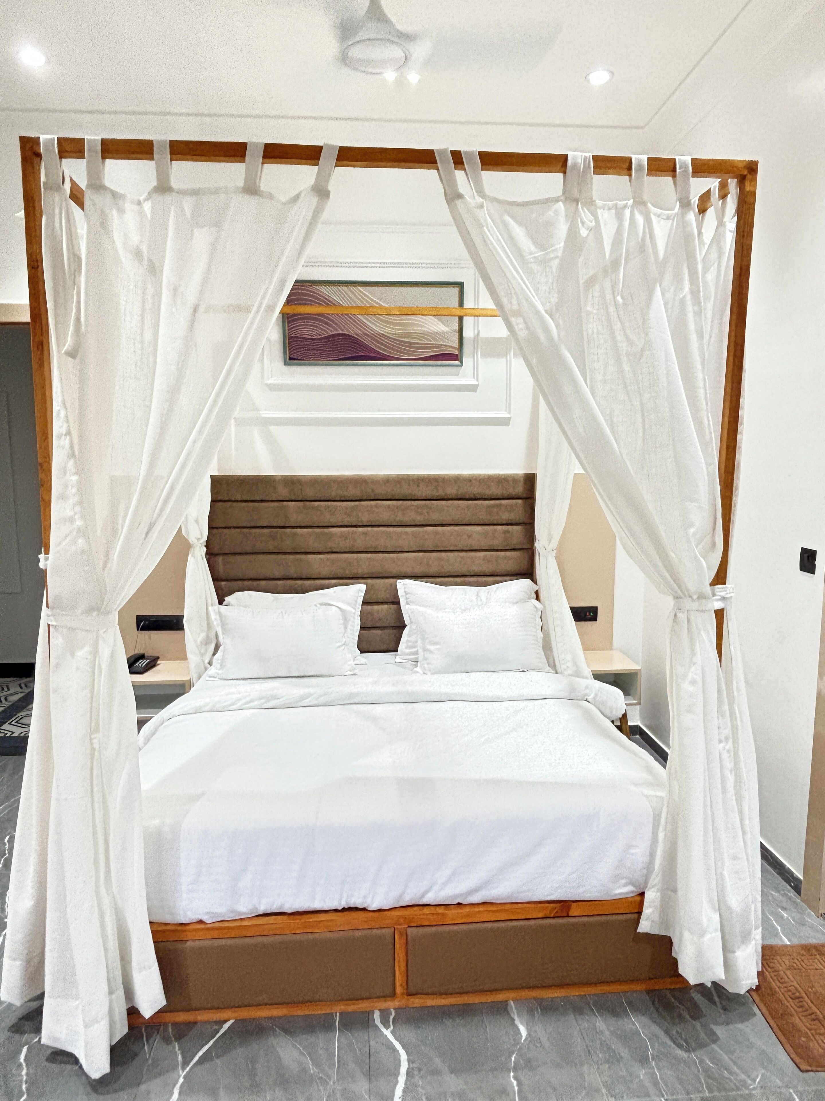 Ein Himmelsbett mit weißer Bettwäsche und einem Holz-Kopfstück.