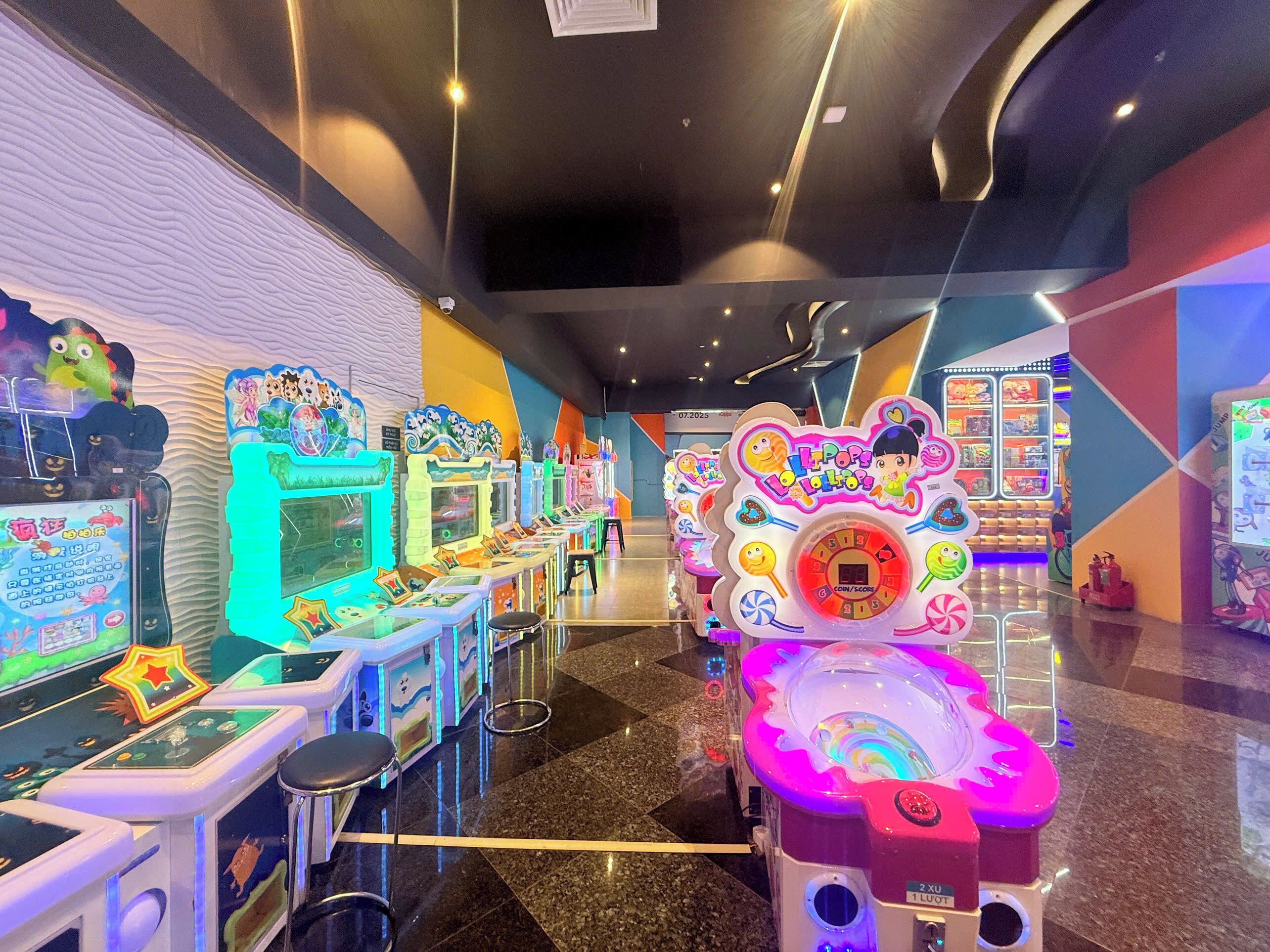 A row of arcade machines with colorful designs and a central game with a digital score display.