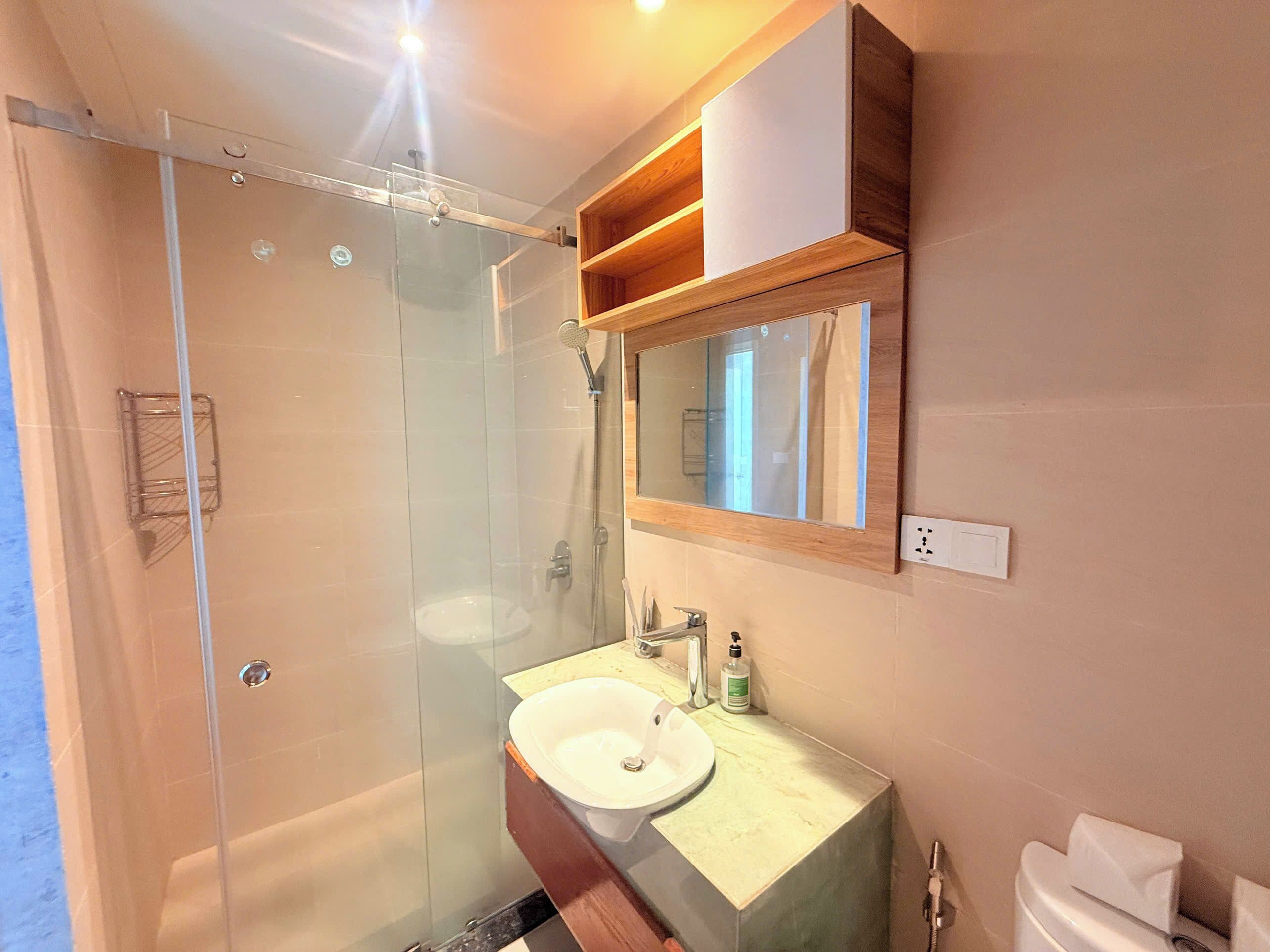 A modern bathroom with a glass shower enclosure, a sink with a mirror above, and a toilet.