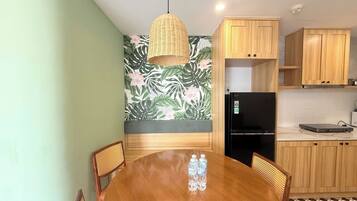 A modern kitchen with wooden cabinets, a black refrigerator, and a round dining table with chairs.