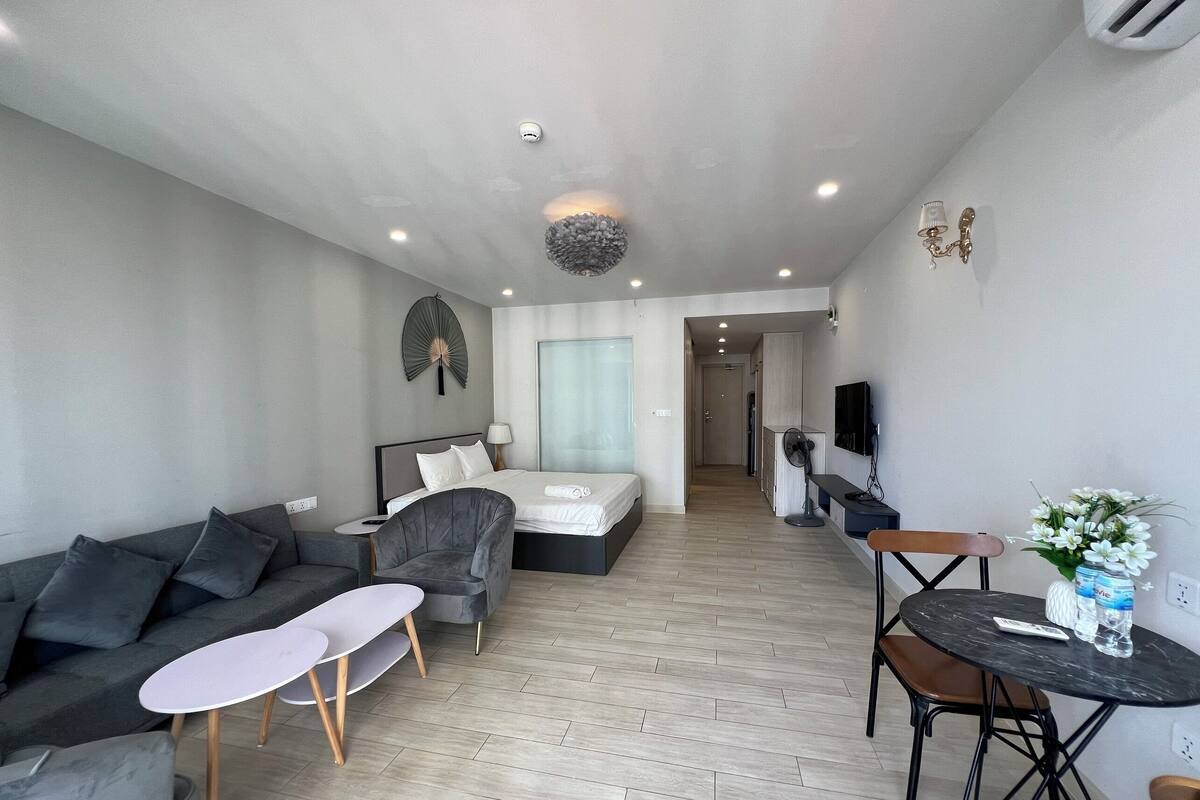 Una habitación de hotel moderna con sofá, cama, una mesita y televisión.