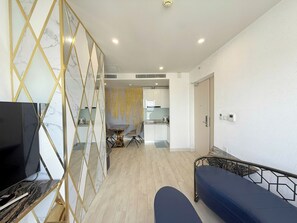 Una sala de estar con televisor, sofá y un separador decorativo.