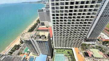 A high-rise hotel with multiple balconies overlooking a beach and the ocean.