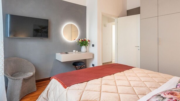 Une chambre à coucher comprenant un lit, une table de chevet avec un miroir, une chaise et une armoire.