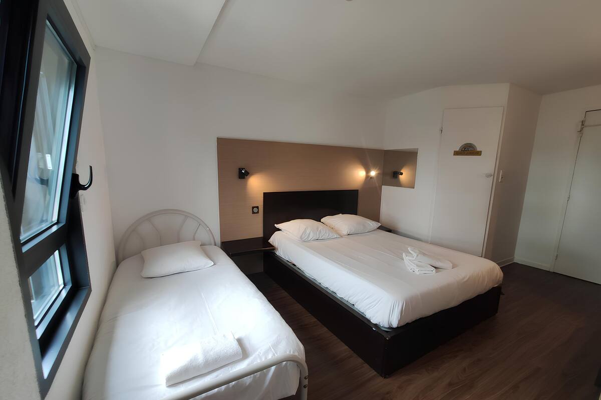 A hotel room with two single beds, a wooden floor, and a white door.