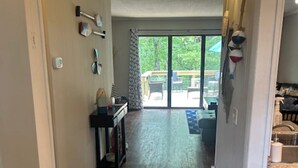 A hallway leading to a patio with a sliding glass door, wooden flooring, and a small table with chairs. - 2-bedroom condo in beautiful Fairfield Bay close to amenities. (Fairfield Bay)