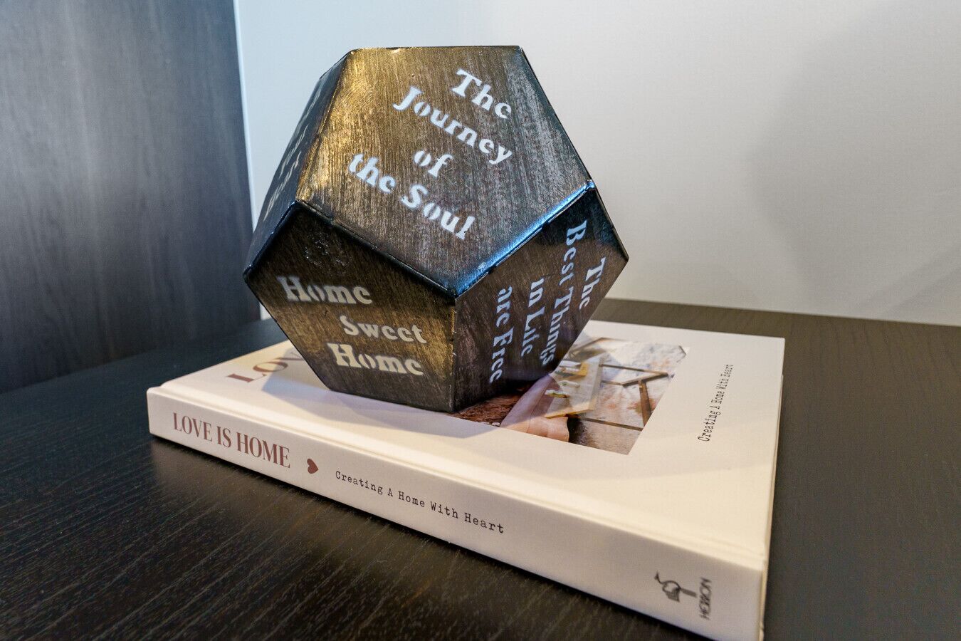 A book titled "LOVE IS HOME" with a decorative wooden cube on top.