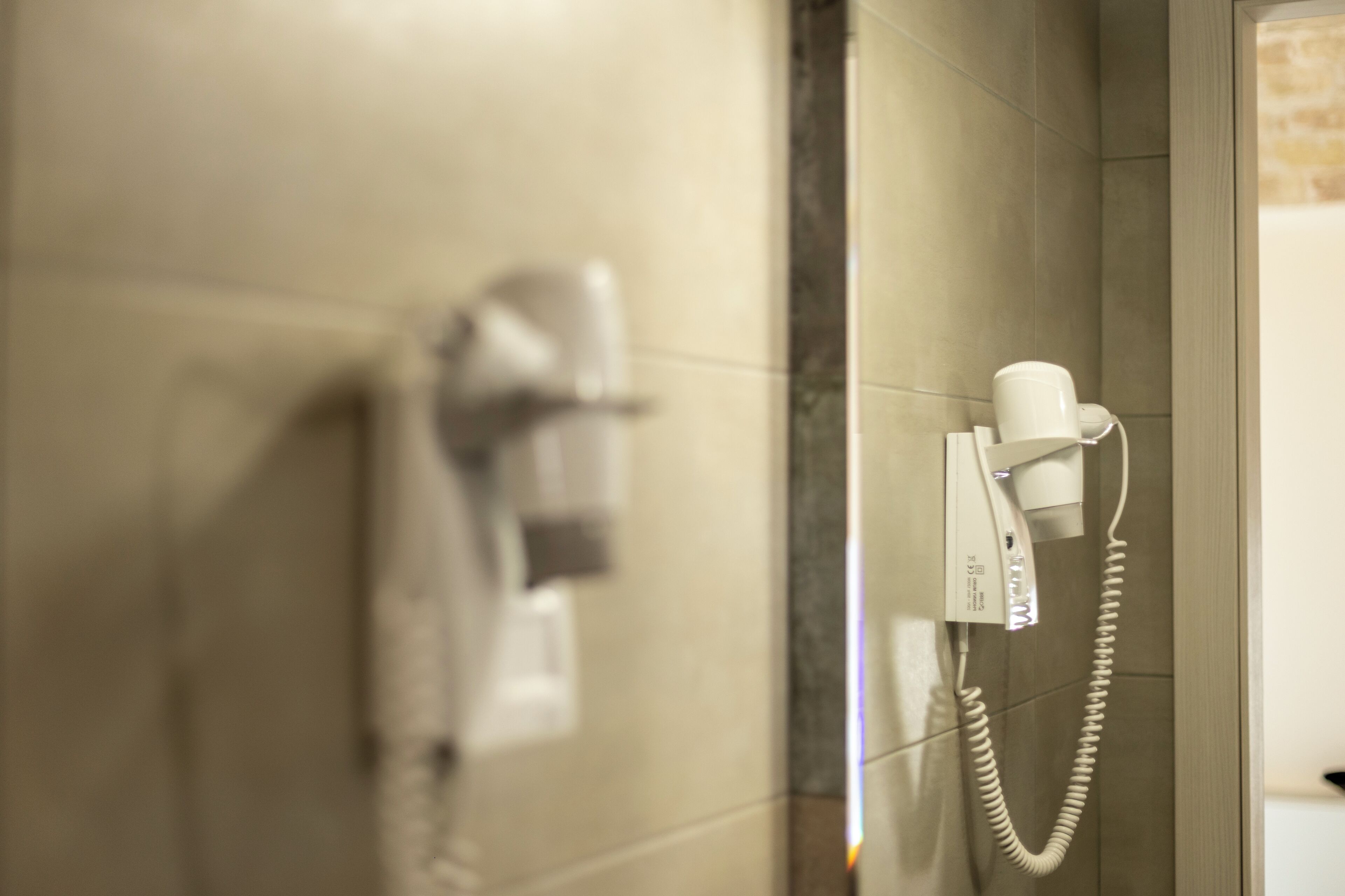 Un baño con secador de pelo y teléfono en la pared.