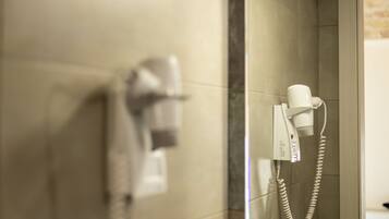Un baño con secador de pelo y teléfono en la pared.