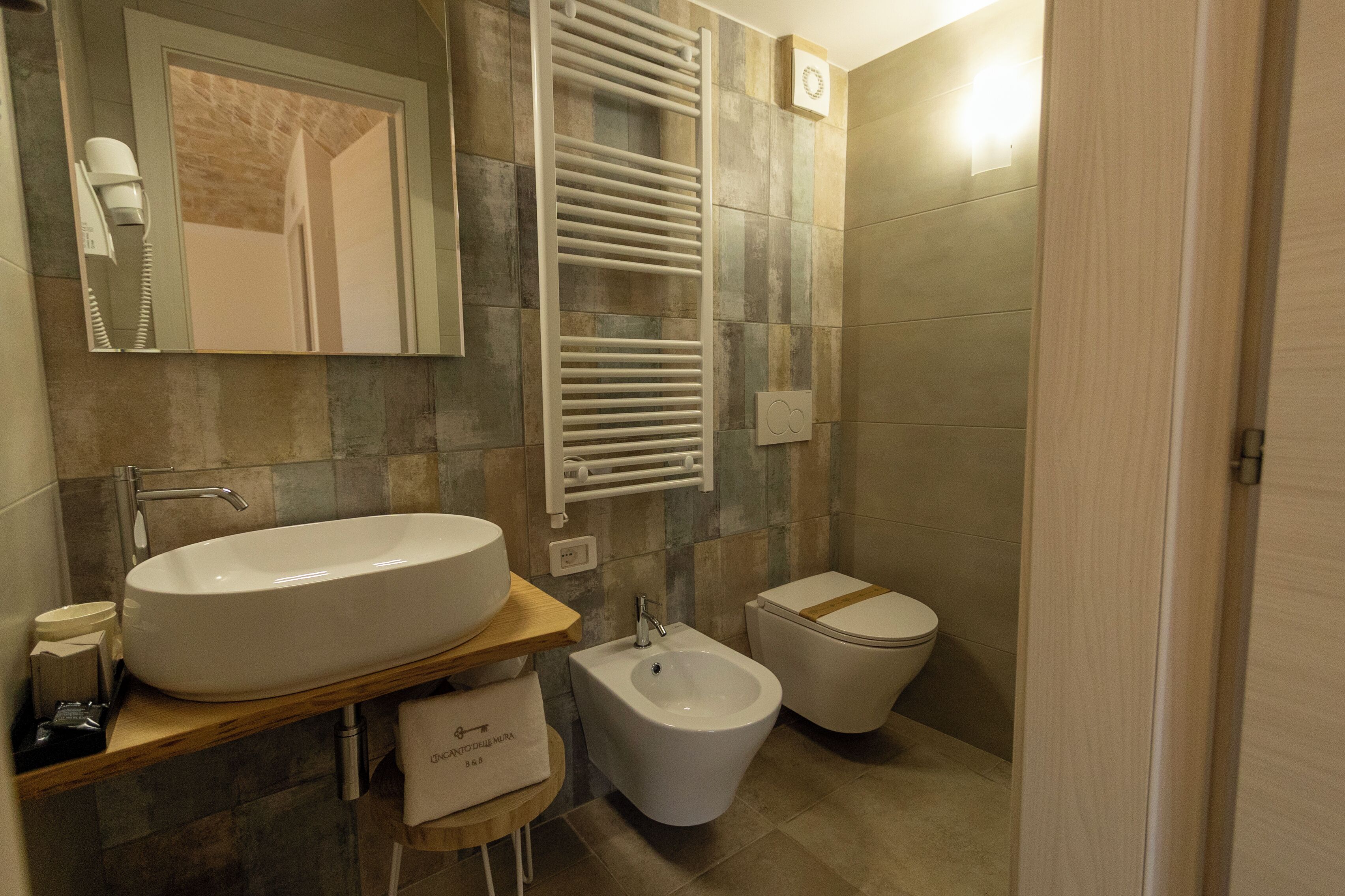 Un baño con lavabo, bidé, inodoro, toallero y espejo.