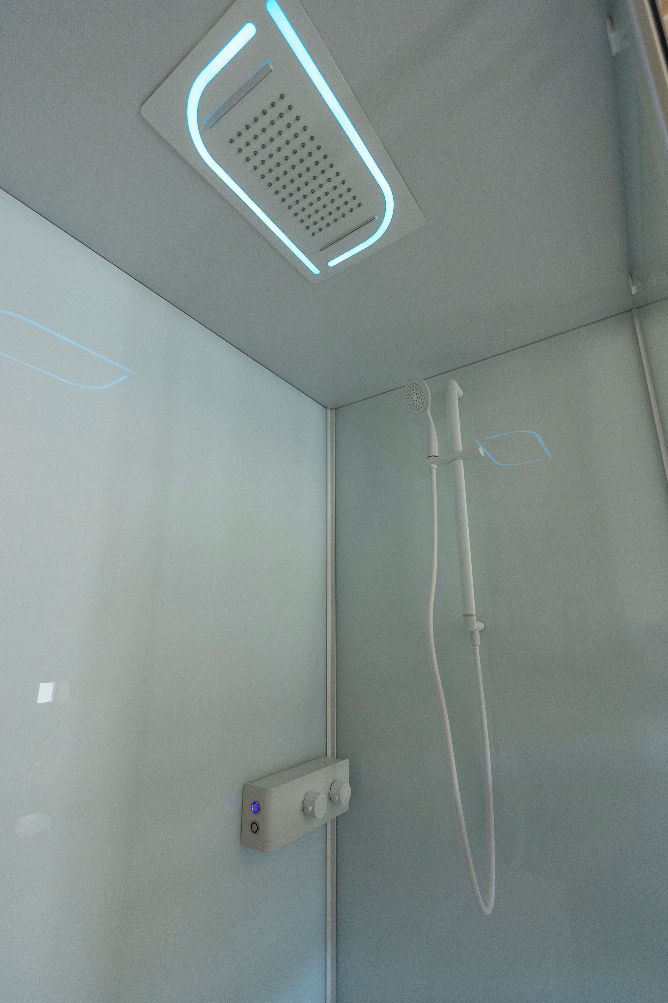 Una ducha moderna con panel de control y cabezal de ducha de mano.