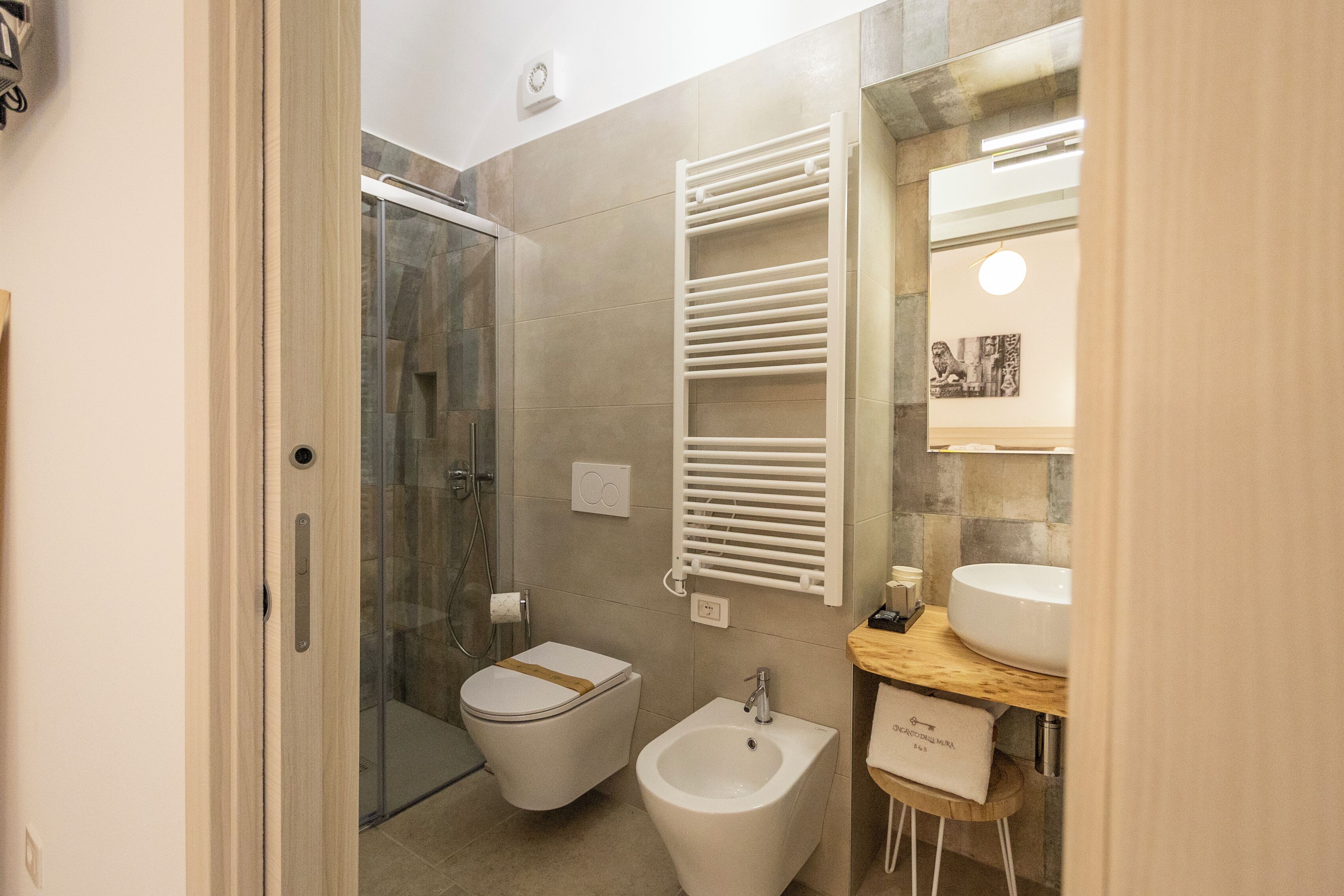 A bathroom with a glass shower enclosure, a toilet, a bidet, and a vanity with a sink.