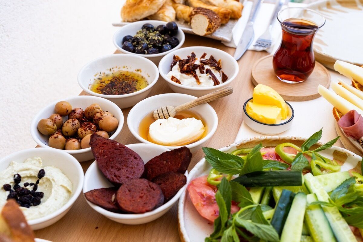 A table with various food items including olives, hummus, olives, and a plate of vegetables.