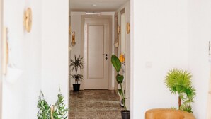 Un couloir avec un revêtement de sol à motifs, une porte et des plantes en pot.