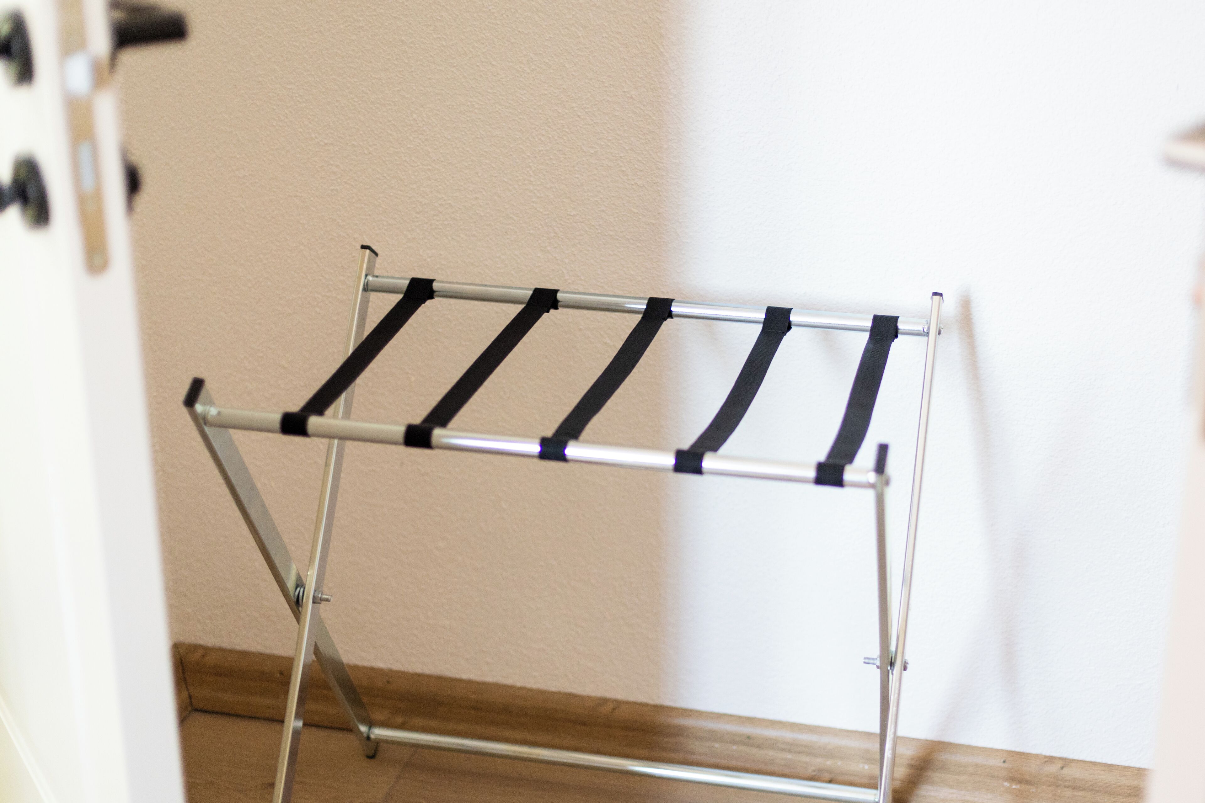 Een metalen droogrek met zwarte banden voor een effen muur.