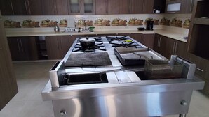 Una cocina con estufa de acero inoxidable, gabinetes de madera oscura y salpicadero de azulejos.