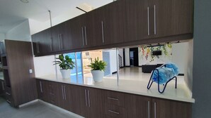 Una cocina moderna con armarios de madera oscura, encimeras blancas y dos plantas en macetas.