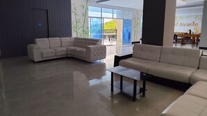 Amplia sala de estar con un sofá en forma de L grande, un sofá más pequeño y una mesa de centro. Una ventana grande ofrece vistas al exterior.