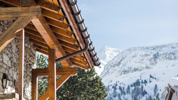 A wooden chalet with stone walls and a snow-covered roof, set against a mountainous backdrop. - Pretty Savoyard chalet 100 metres from the slopes (Val-d'Isère)