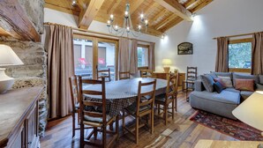 A cozy room with a wooden ceiling, a dining table with chairs, a sofa, and a chandelier. - Pretty Savoyard chalet 100 metres from the slopes (Val-d'Isère)