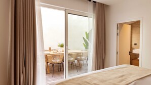 A hotel room with a sliding glass door leading to a balcony with a dining table and chairs. - Maison Legendre - Luxury Townhouse with 5BDR & AC in Batignolles (Paris)