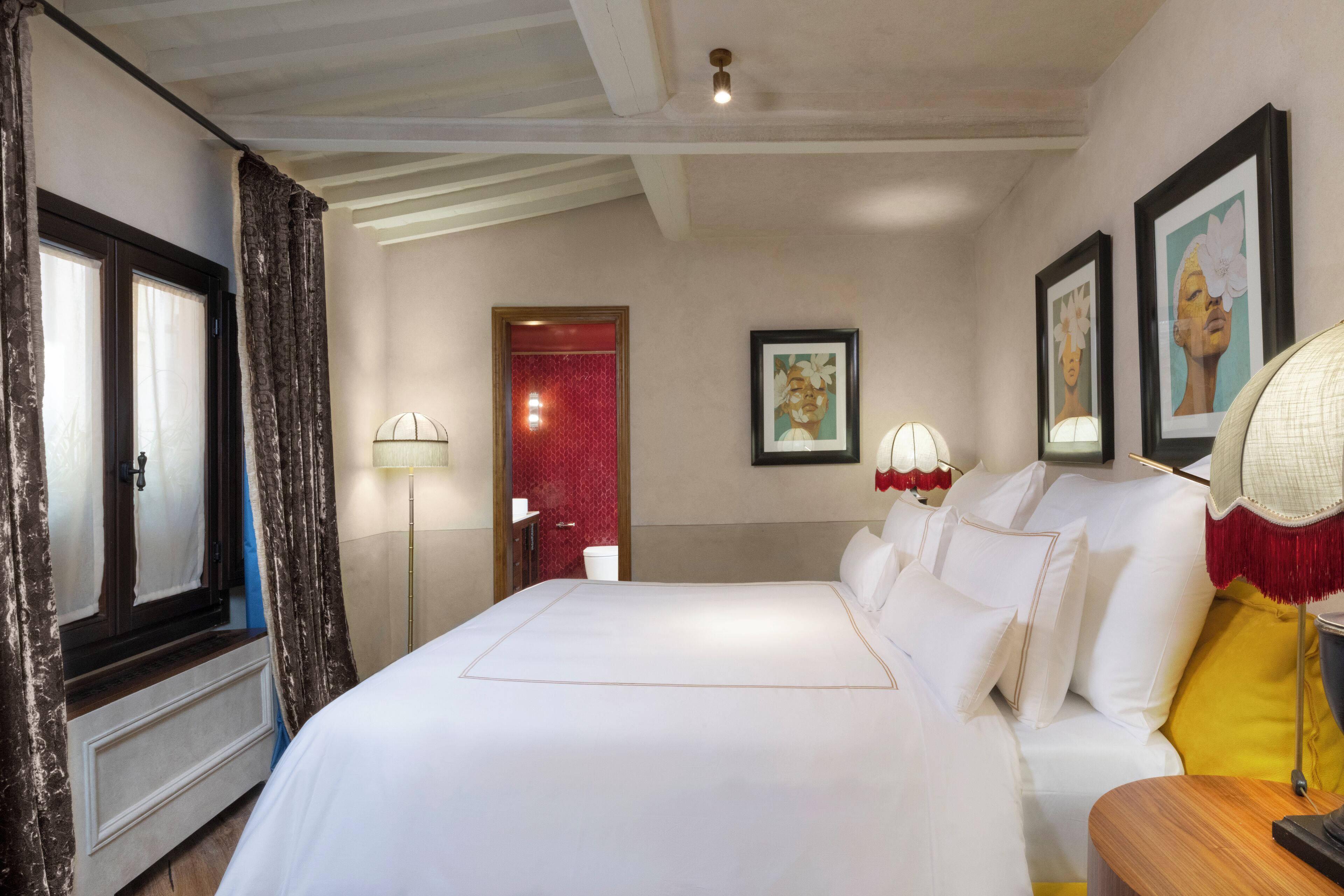 A hotel room with a large bed, a bedside table, a lamp, and a framed picture on the wall.