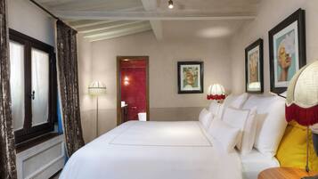 A hotel room with a large bed, a bedside table, a lamp, and a framed picture on the wall.