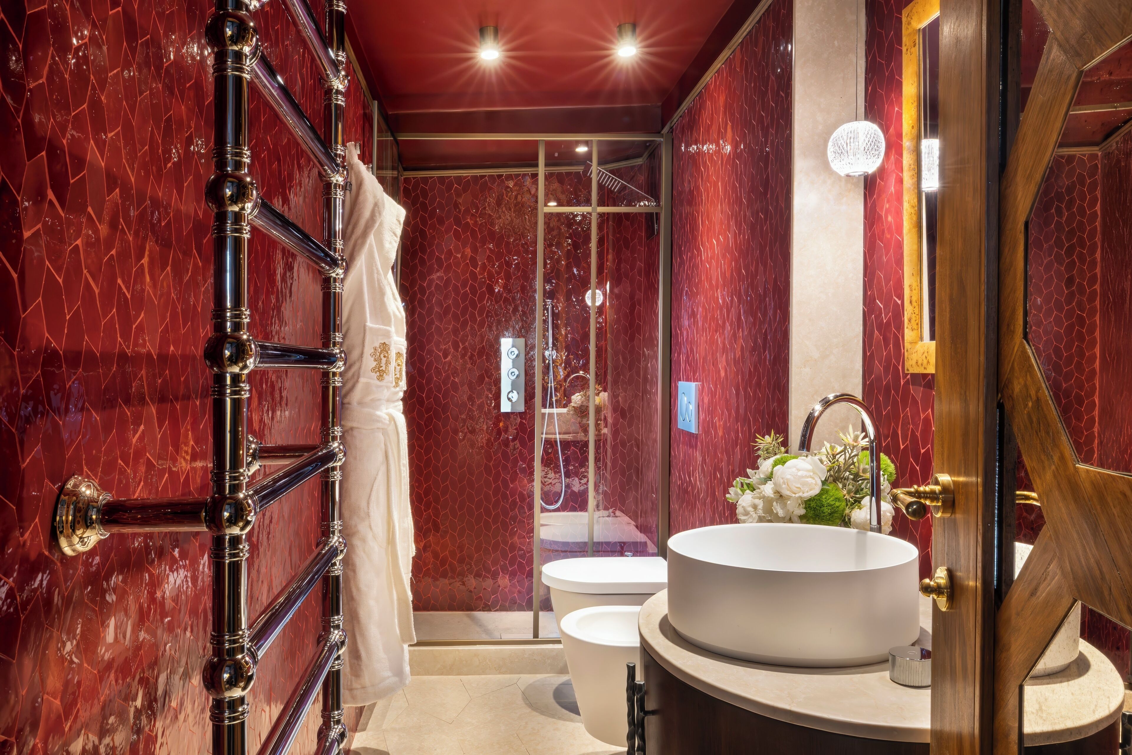 A bathroom with a marble wall, a white sink, and a glass shower enclosure.