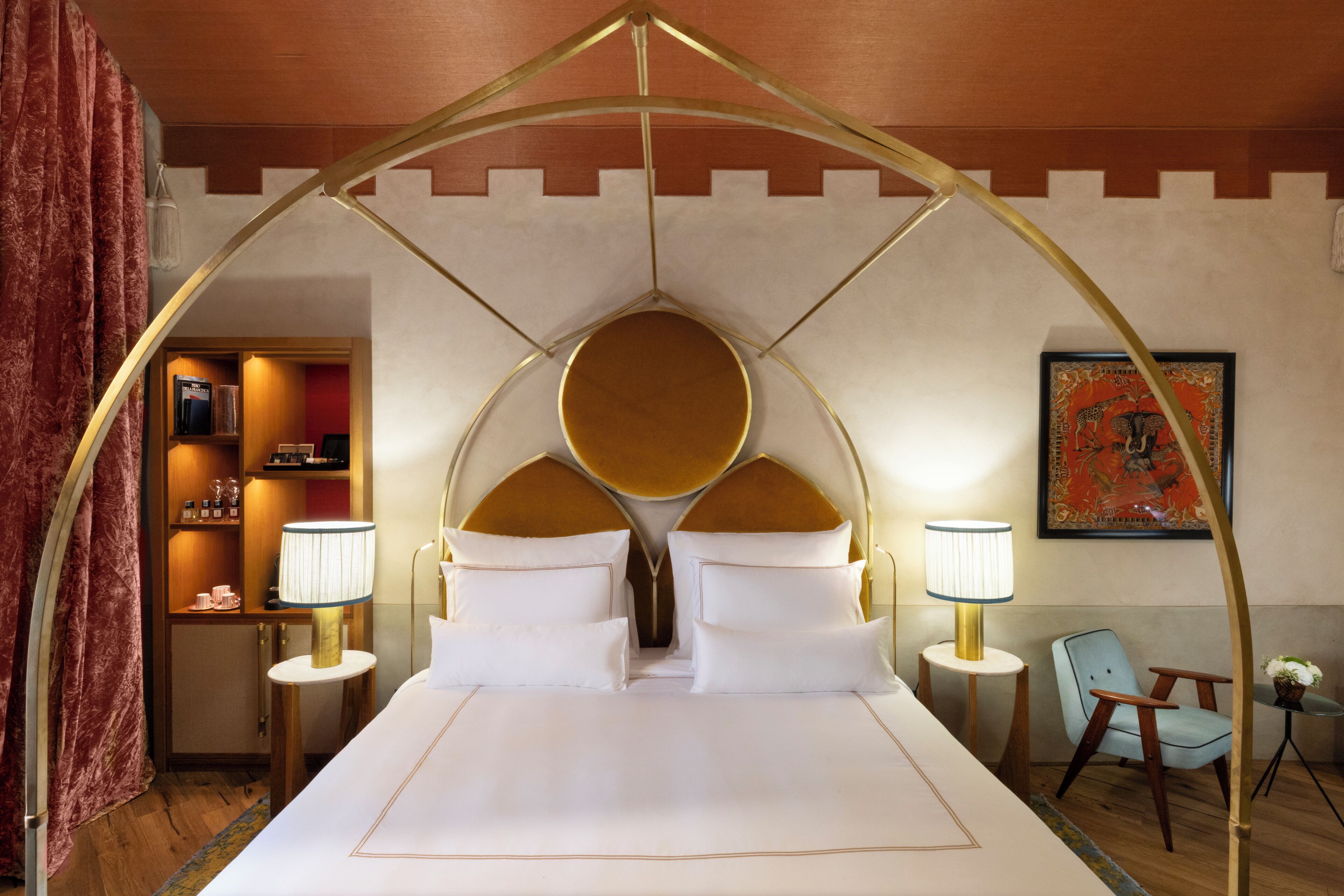 Une chambre d’hôtel avec un grand lit, deux lampes de chevet, une chaise et une petite table sur laquelle est posée une plante.