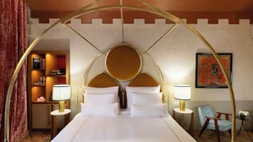 Une chambre d’hôtel avec un grand lit, deux lampes de chevet, une chaise et une petite table sur laquelle est posée une plante.