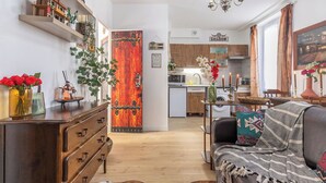 A modern living room with a wooden dresser, a sofa with a blanket, and a dining area with a chandelier. - La Tanière du Cowboy (Orléans)