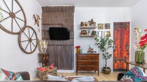 A living room with a television, wooden furniture, decorative items, and a rustic door. - La Tanière du Cowboy (Orléans)