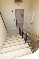 Un escalier avec des marches en marbre et une rampe dorée menant à une porte.