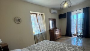 Een slaapkamer met een groot bed, een kaptafel, een spiegel en een plafondventilator.