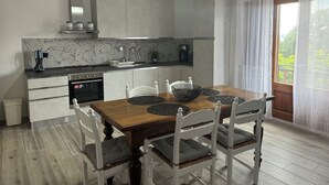 Een moderne keuken met witte kasten, een houten eettafel en uitzicht op groen.