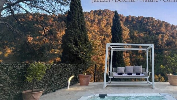 Un jardín con una silla mecedora, una piscina y un muro de piedra.
