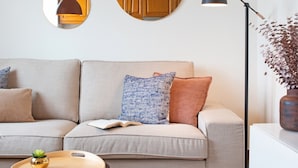 Un salon moderne avec un canapé, des miroirs ronds, une lampe sur pied et un pouf à motifs.