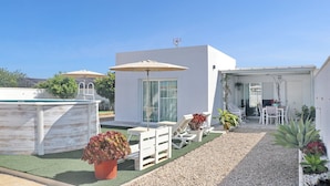 Uma área de varanda moderna ao ar livre com piscina, espreguiçadeiras e mesa de jantar.